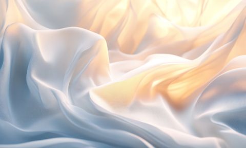 A close-up of soft, flowing fabric in gentle waves, illuminated by warm golden and cool blue lighting, creating a serene and airy ambiance.