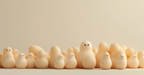 A collection of rounded, minimalist wooden figures with soft, warm beige tones. Some figures have simple, happy facial expressions, set against a neutral background.